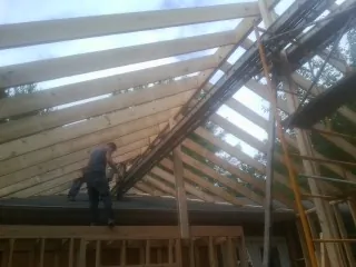 Rafters going up over a new addition with a worker on the wall in Hannibal