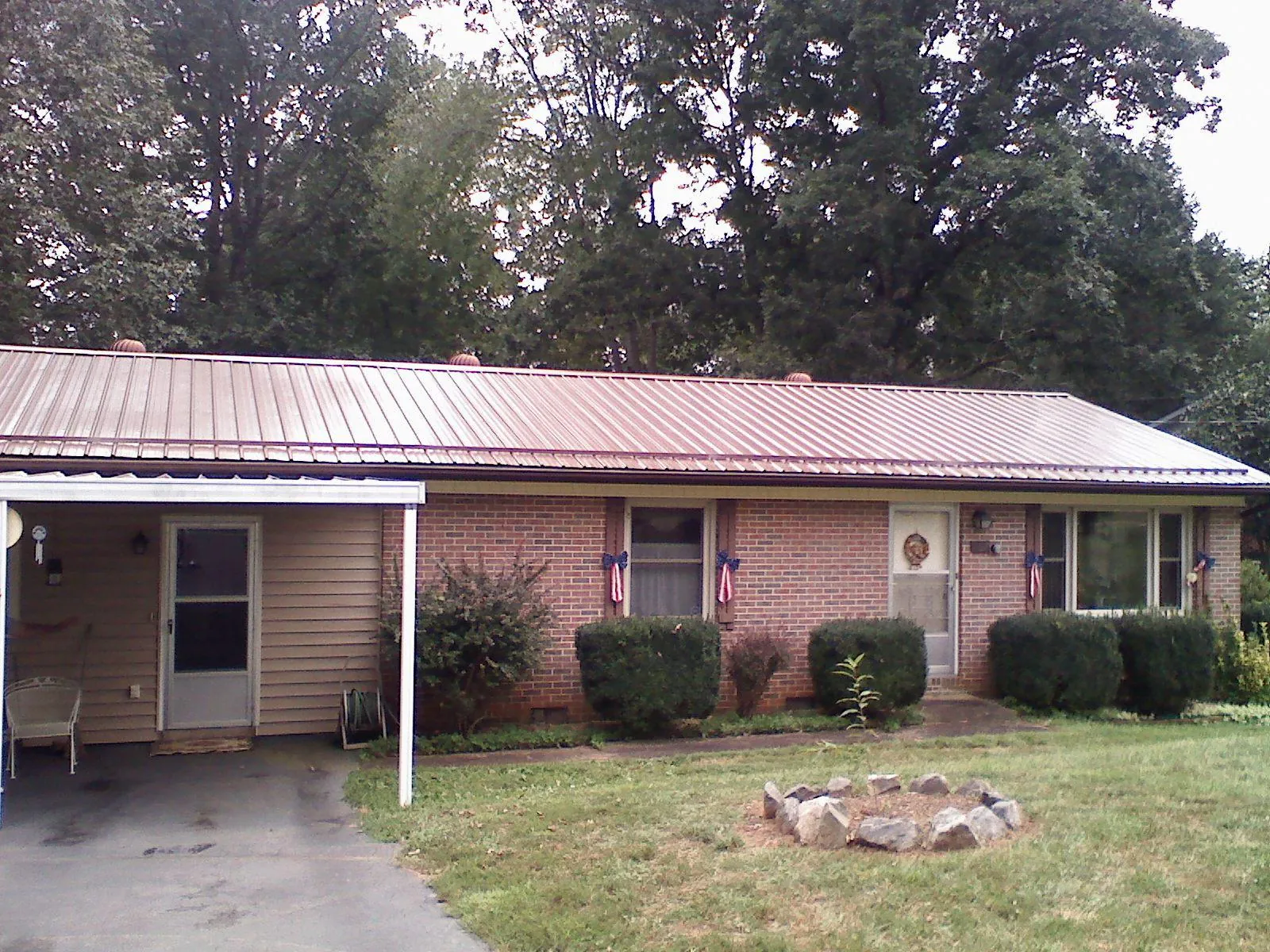 Bronze metal roof and carport on a brick ranch home — Roof Repair work by our crew in Hannibal