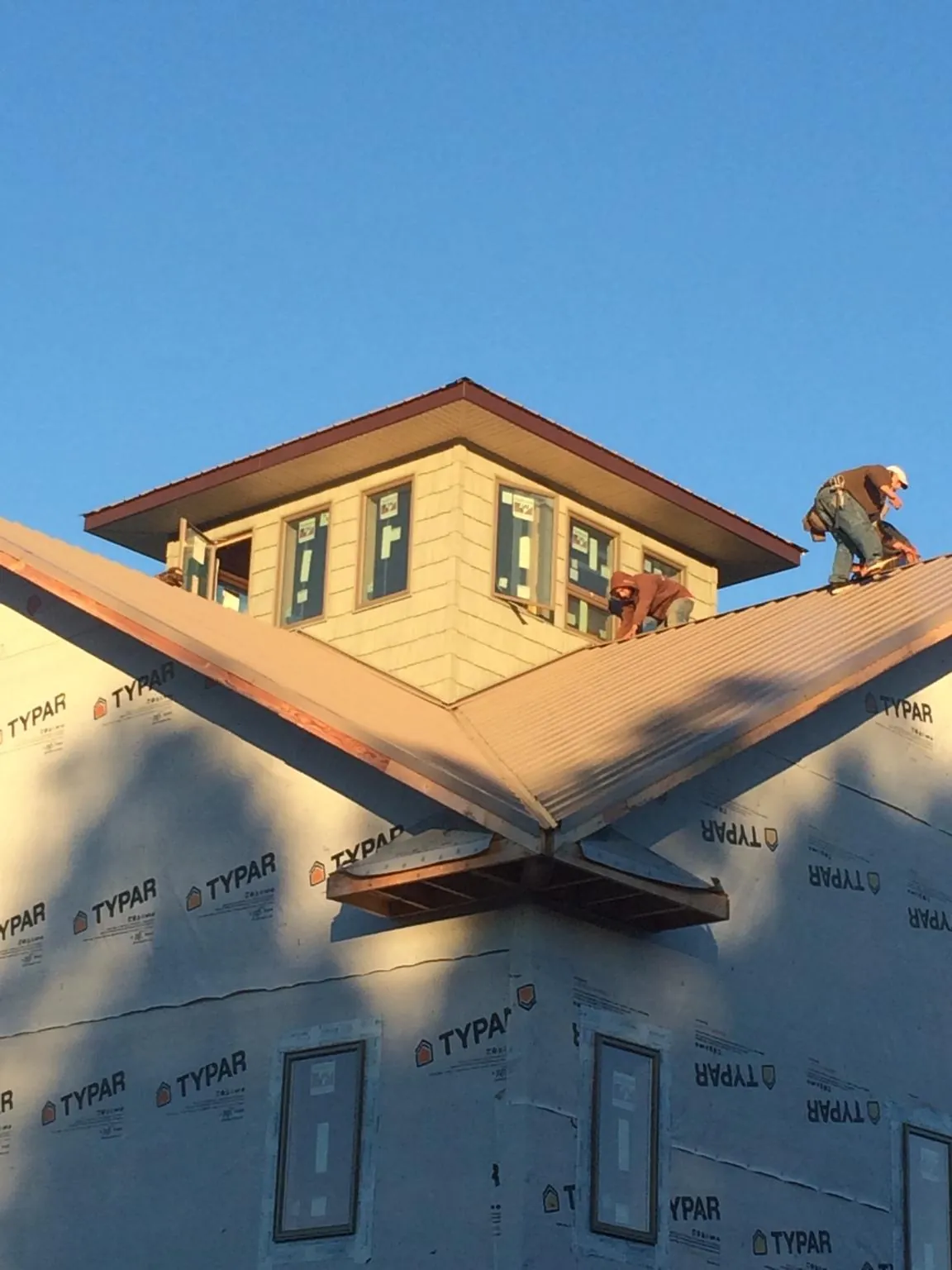 Roofers working around a rooftop cupola on a new metal roof at sunset — Roof Waterproofing in Hannibal by Roofing Brothers